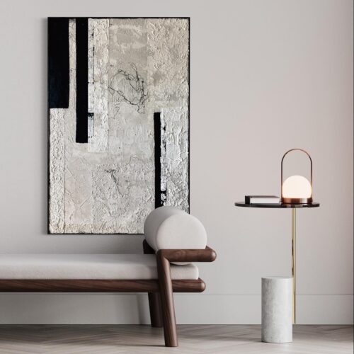 Minimalistyczny obraz 120x70 w czerni i naturalnych kolorach w minimalistycznym wnętrzu, zawieszony nad nowoczesnym, drewnianym szezlongiem, obok stoi minimalistyczna lampka